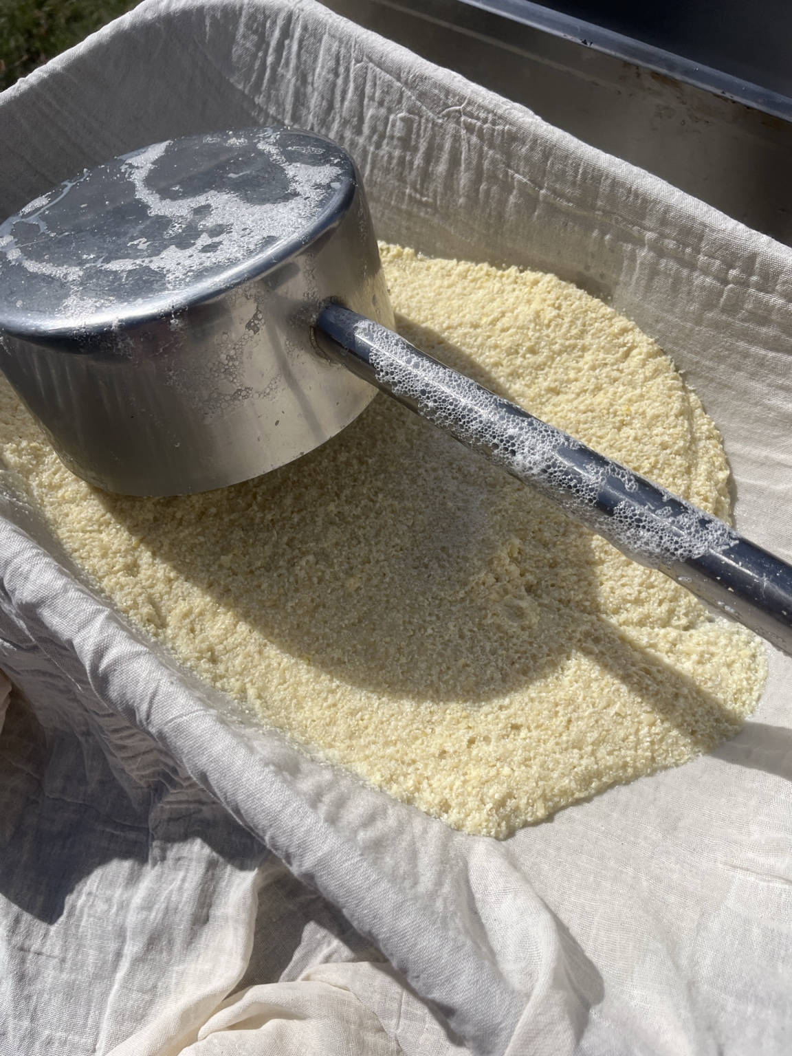 Tofumasse im Tuch mit großer Kelle bei der Verarbeitung im Hof